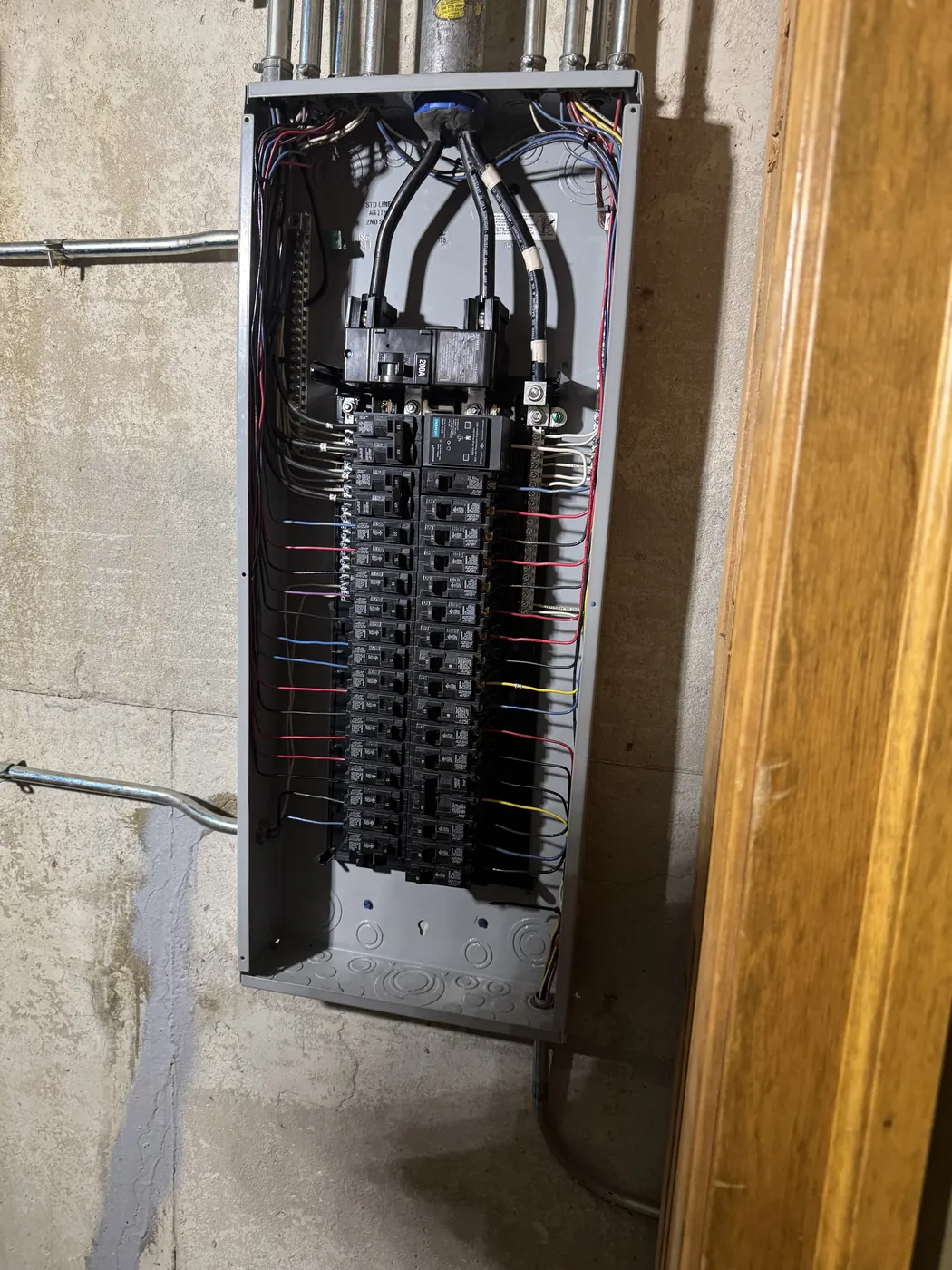 Open electrical service panel with newly wired breakers in a customer home